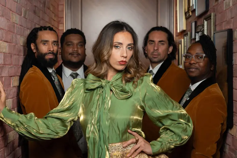 Lexie and her band lined up in a corridor, styled in green and gold