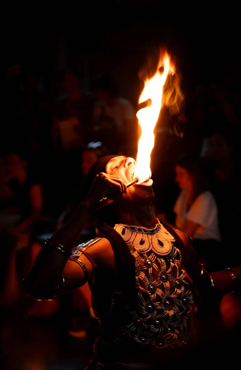 Fire performer mid-act, flames tracing arcs in the dark